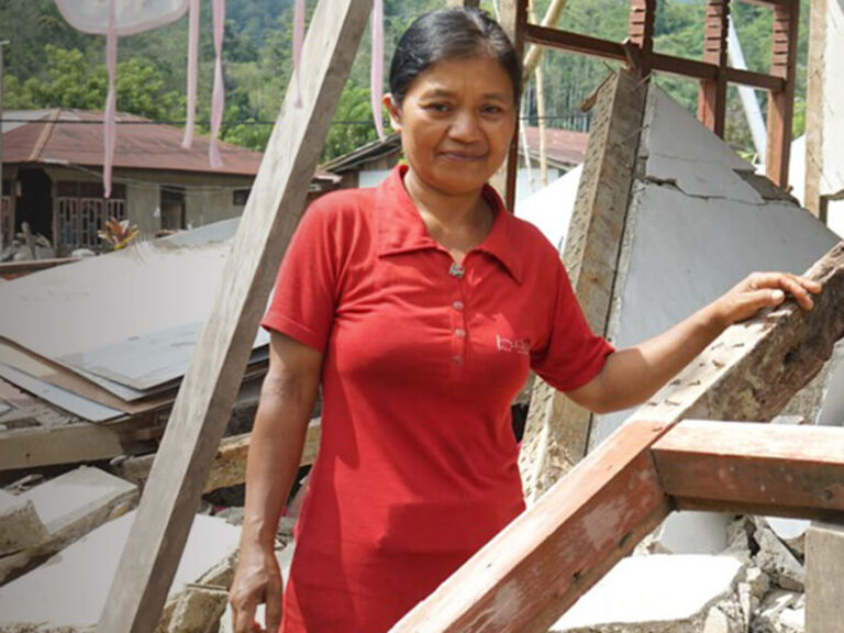 Woman standing amongst rubble in Indonesia