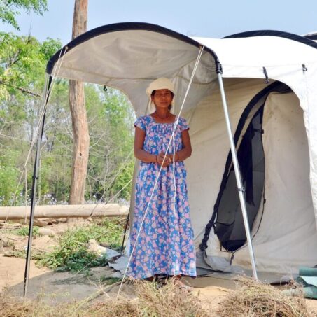 Lady standing with hands clasped in front of a Shelterbox home