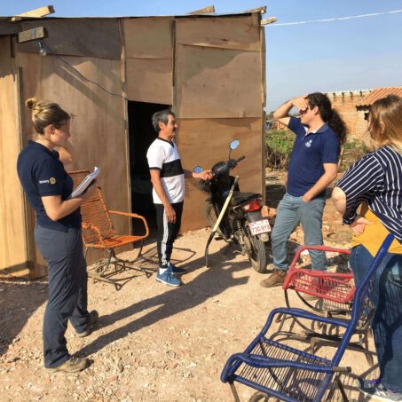 A group of people talking outside a wooden shelter
