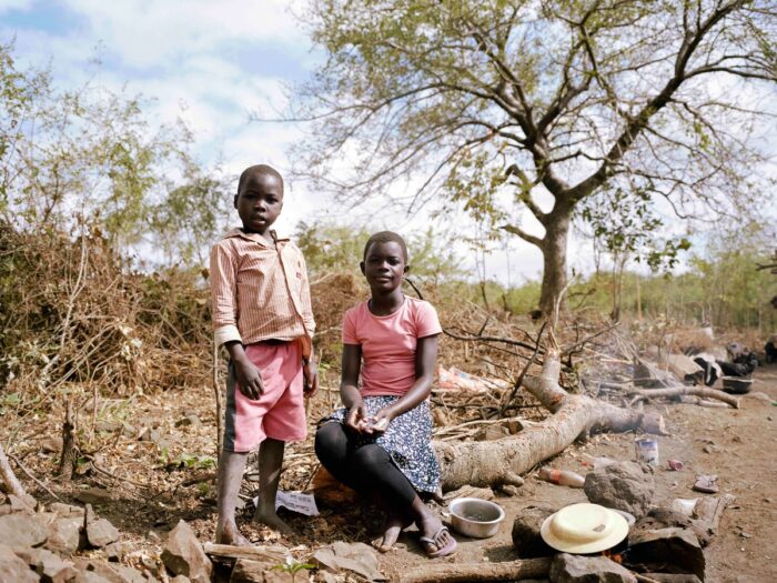 2 children are posing in front of a tree