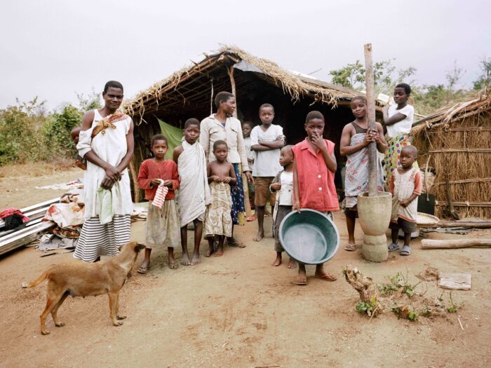 A family posing outside their makeshift shelter in Malawi