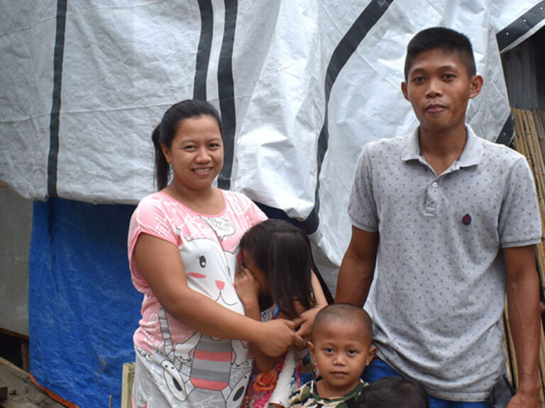 A family of 5 posing in front of their home
