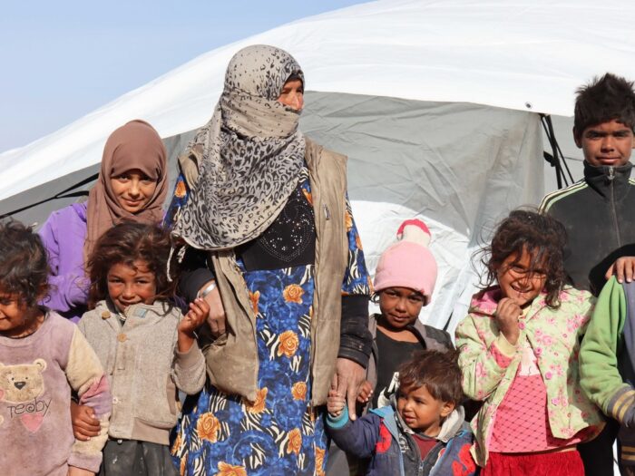 A woman surrounded by children in front of a tent