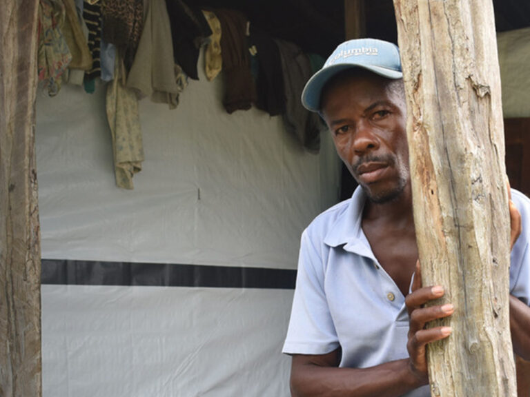 A man and a boy outside a makeshift shelter