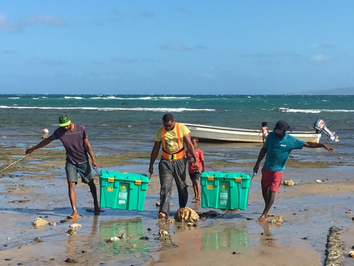 Three men carrying green boxes