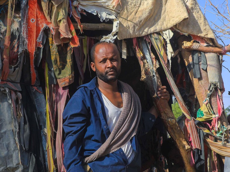 Yemeni man standing in front of shelter