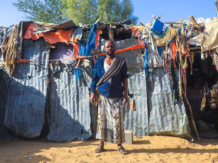 Yemeni man standing in front of shelter
