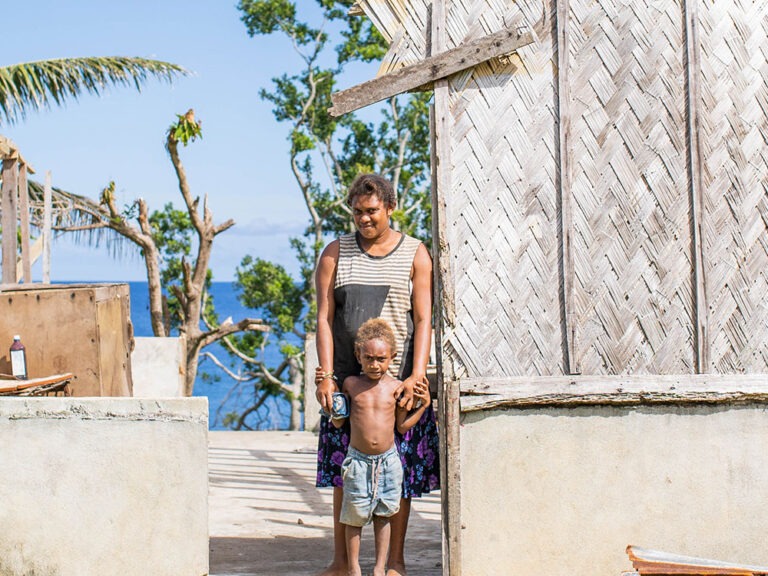 woman and child stand in destroyed home after cyclone harold hit vanuatu