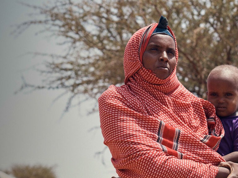 Somaliland woman in red headscarf holding child by olly burn