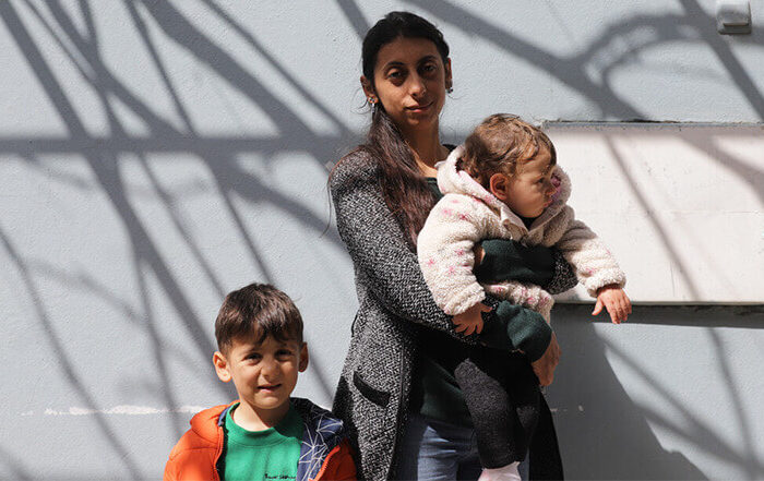 A women holding her baby daughter with her young son