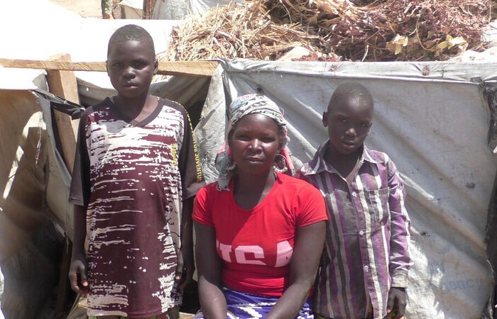 Woman and two boys in front of a shelter in Cameroon