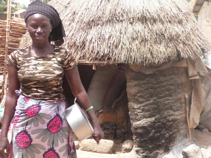 A woman standing in the outdoor area of her home, smiling at the camera