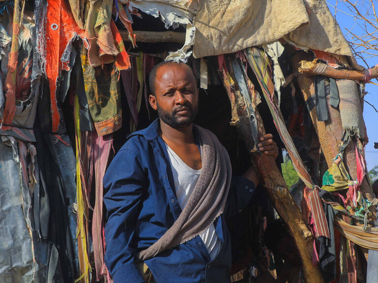 Man standing outside a temporary shelter in Yemen
