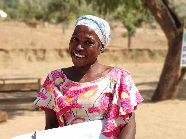 Woman smiling at the camera holding aid in Cameroon