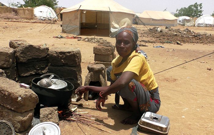 Woman crouching while cooking in Cameroon