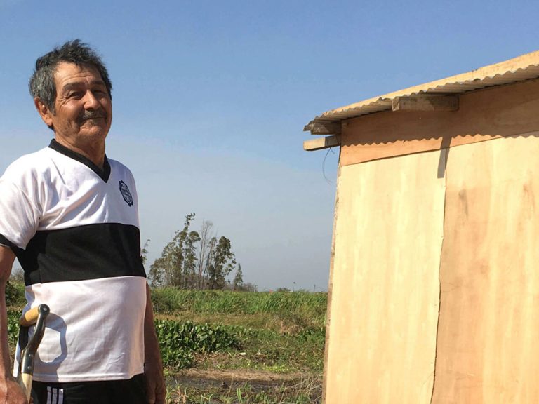 Man holding shovel outside home in Paraguay