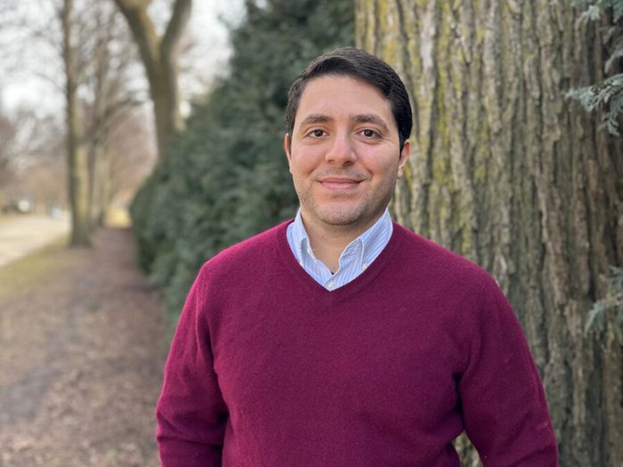 Man wearing a red jumper standing next to a tree