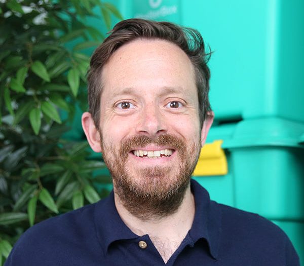 Man wearing blue polo shirt in front of green background