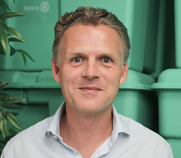 Man wearing white shirt in front of green boxes
