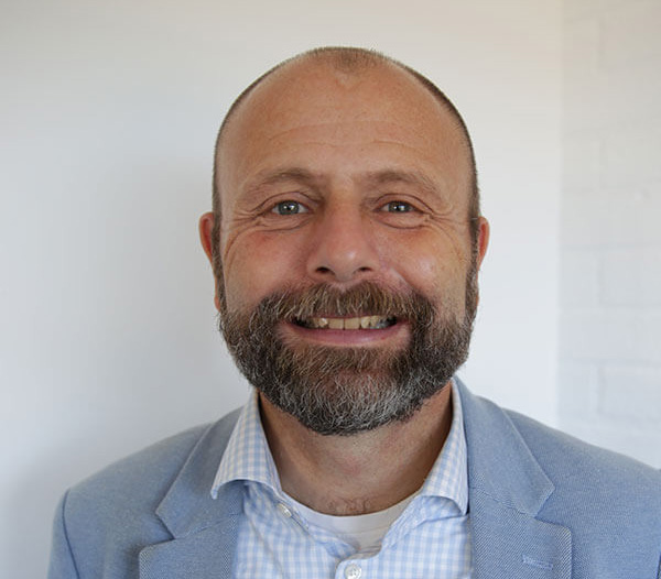 Man wearing blue jacket against a cream background