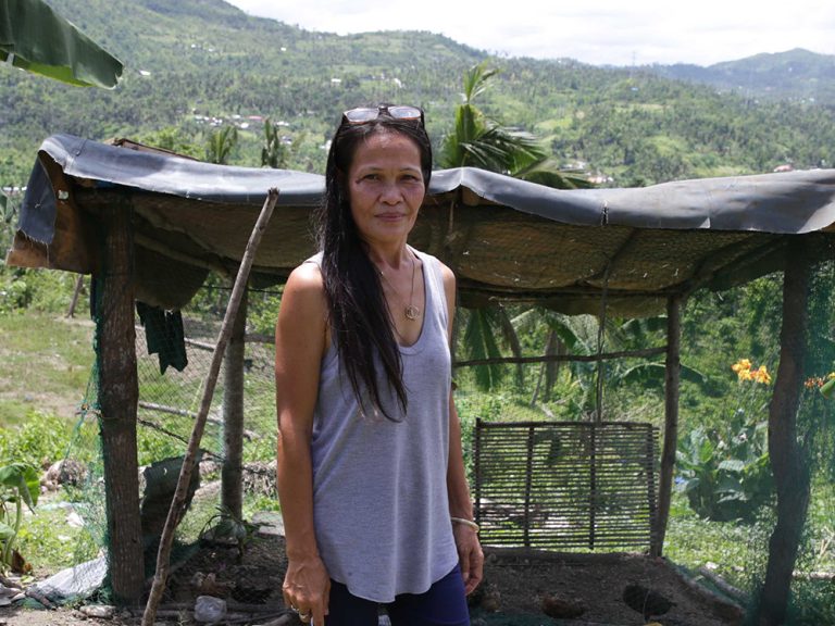 Woman standing in front of damaged building in the Philippines