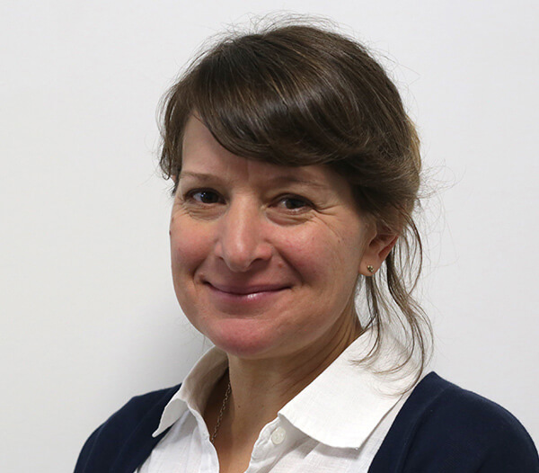 Woman with brown hair in front of a cream background