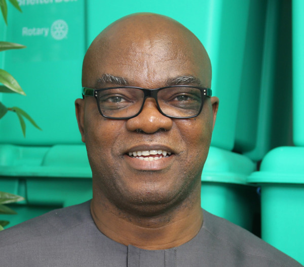 Man wearing grey shirt in front of green boxes