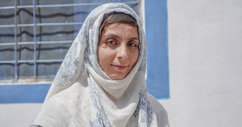 Woman wearing white and blue headscarf smiling at the camera