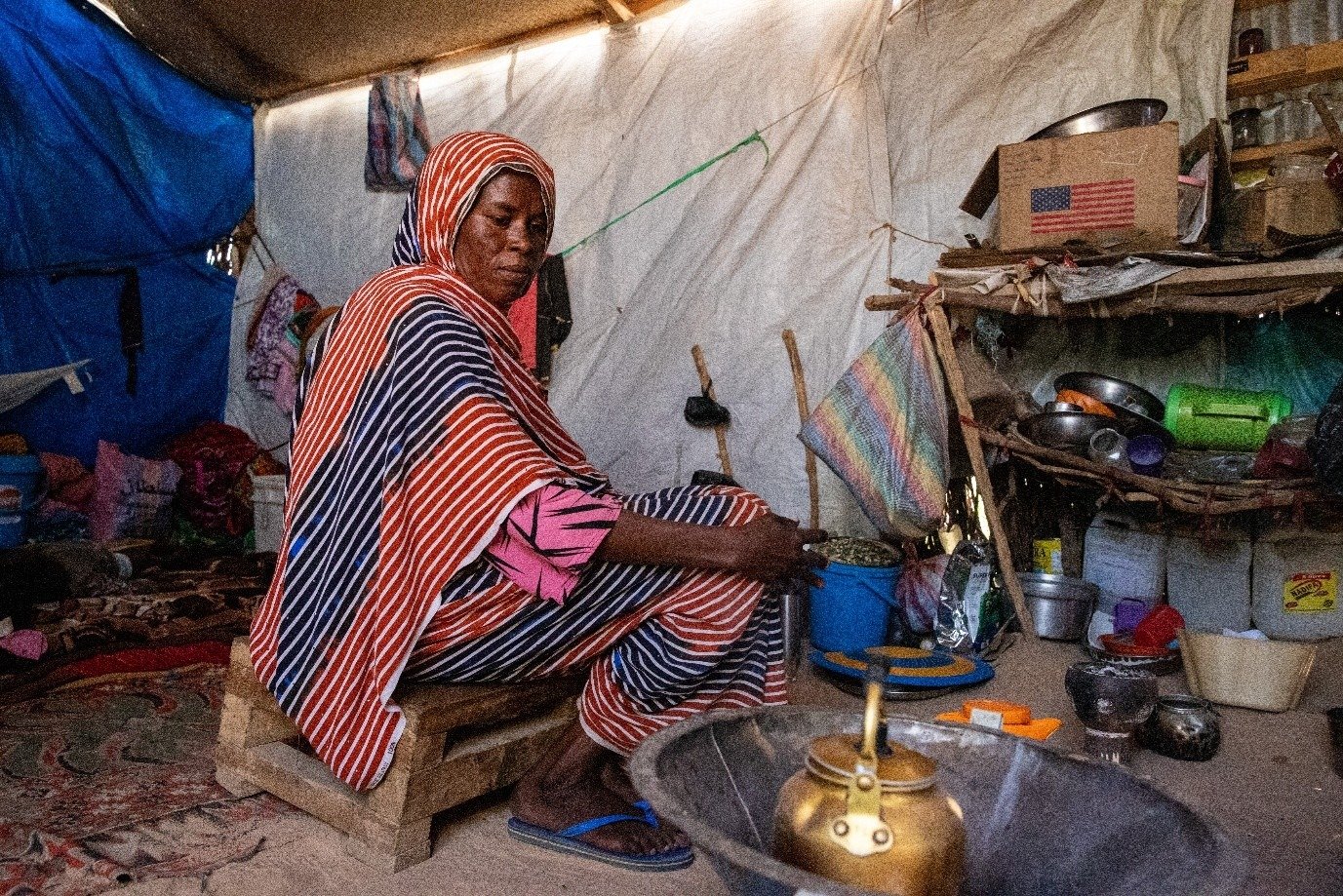 woman making tea in a displacement camp, in Chad after fleeing war in Sudan.
