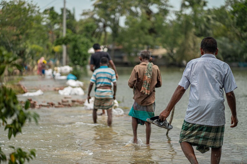 Flooding damage in Bangladesh after a cyclone. People walk through water.