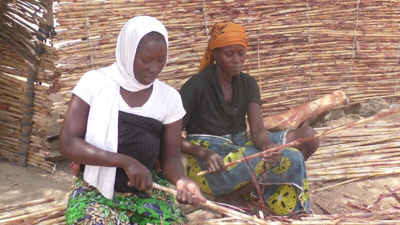 Two women sat down with crops in a displacement camp in Cameroon.