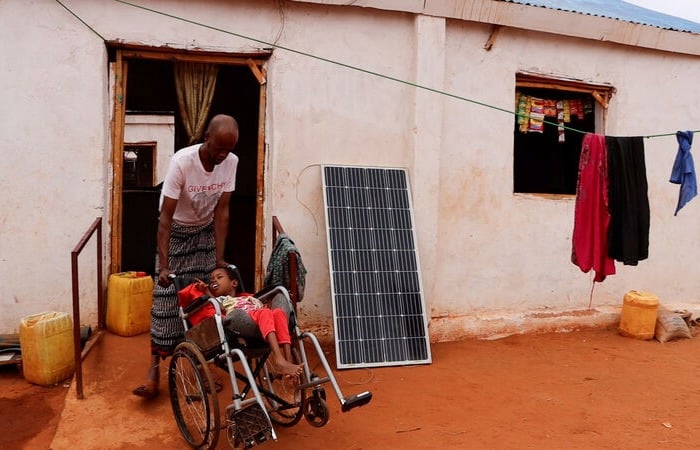 A semi durable shelter with two people outside in Somalia.