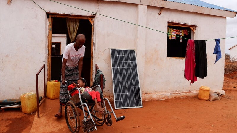 A man and his disabled daughter outside a home.