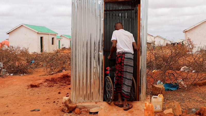 A man and girl in a wheelchair going into a shelter.