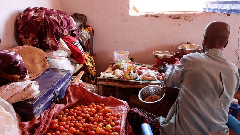 A man with his fruit inside a shelter.