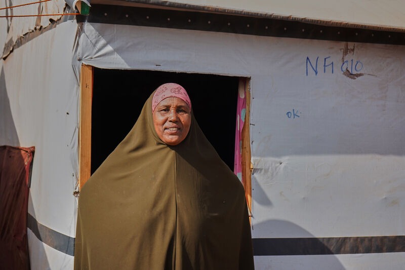 A woman standing outside a tent in a displacement camp in Somalia.