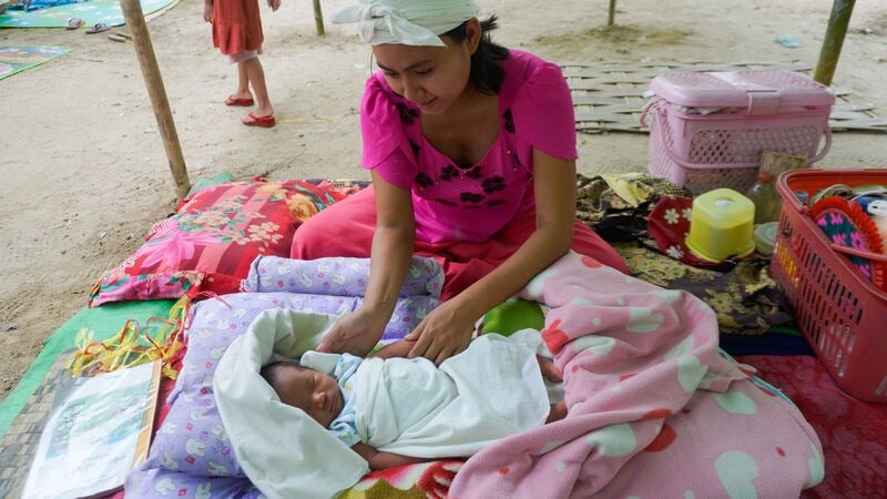 A woman looking after a baby in an emergency shelter after an earthquake.