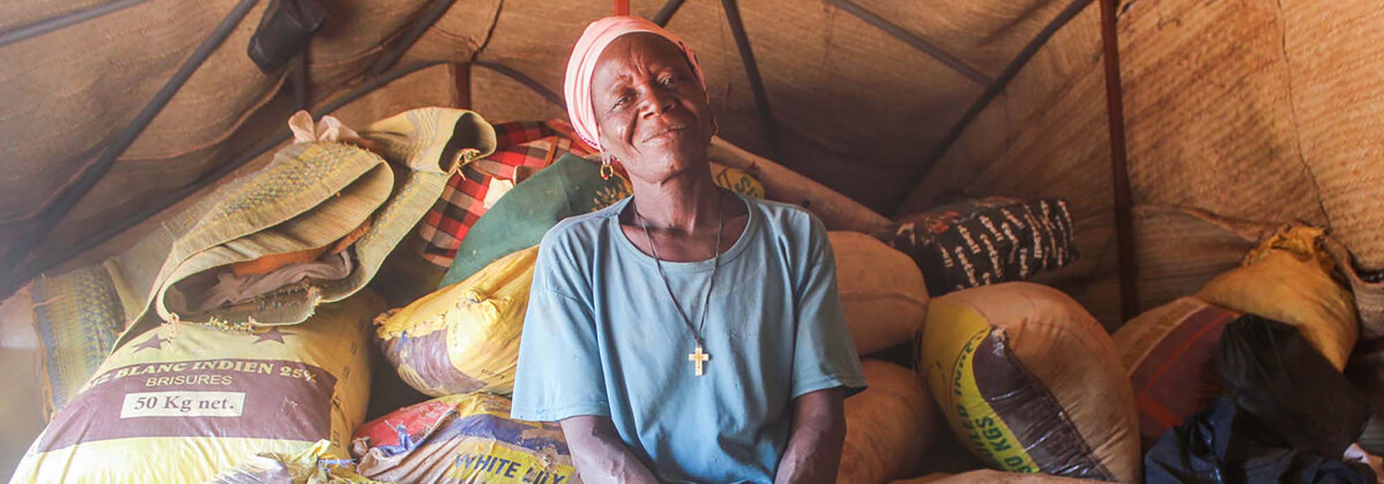 A woman looking at the camera sitting on emergency shelter aid smiling.