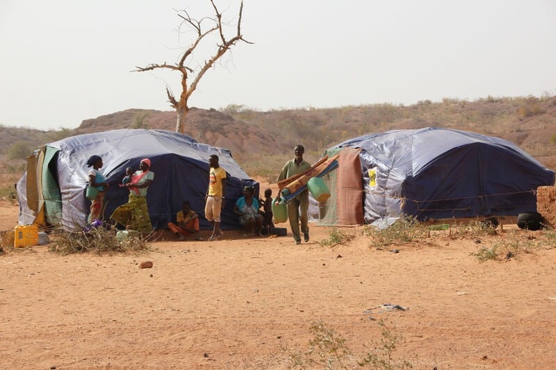 People standing next to emergency shelters.