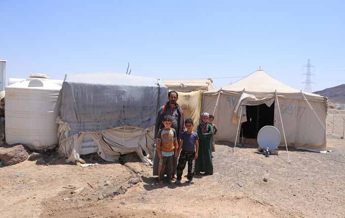 A man outside an emergency shelter with children.