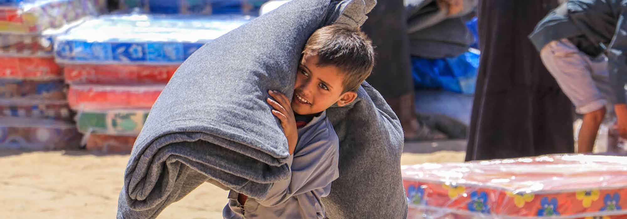A boy carrying a mattress as part of aid distributions in Yemen.