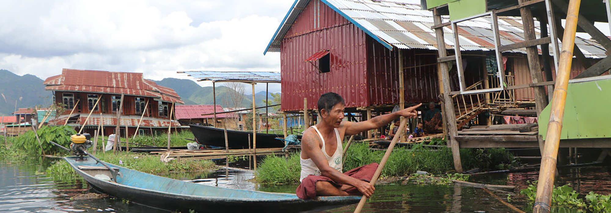 A man in a boat next to broken shelters.