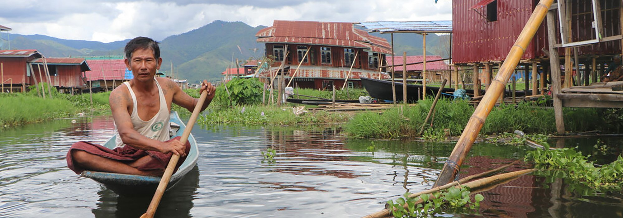 A man in a boat next to broken shelters.