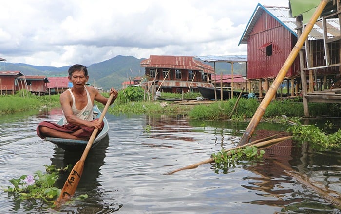 A man in a boat next to broken shelters.